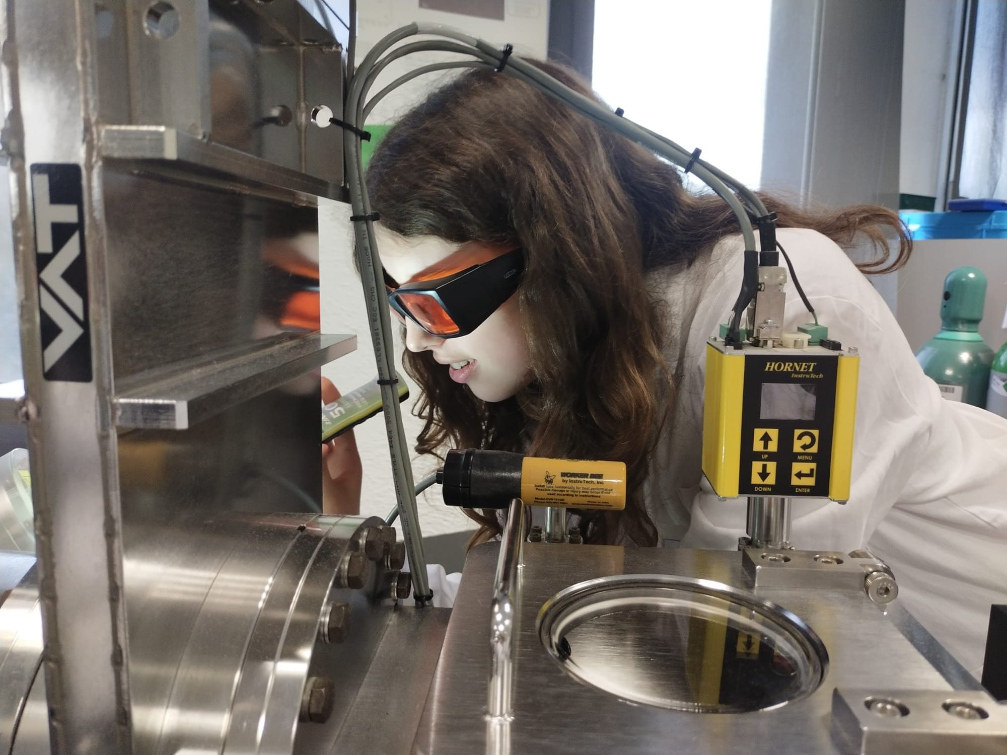 Scientist wearing safety goggles analyzing a machine during the Bojos per l'Energia intensive sustainable energy course by Fundació Catalunya La Pedrera and IREC for Batxillerat science students.