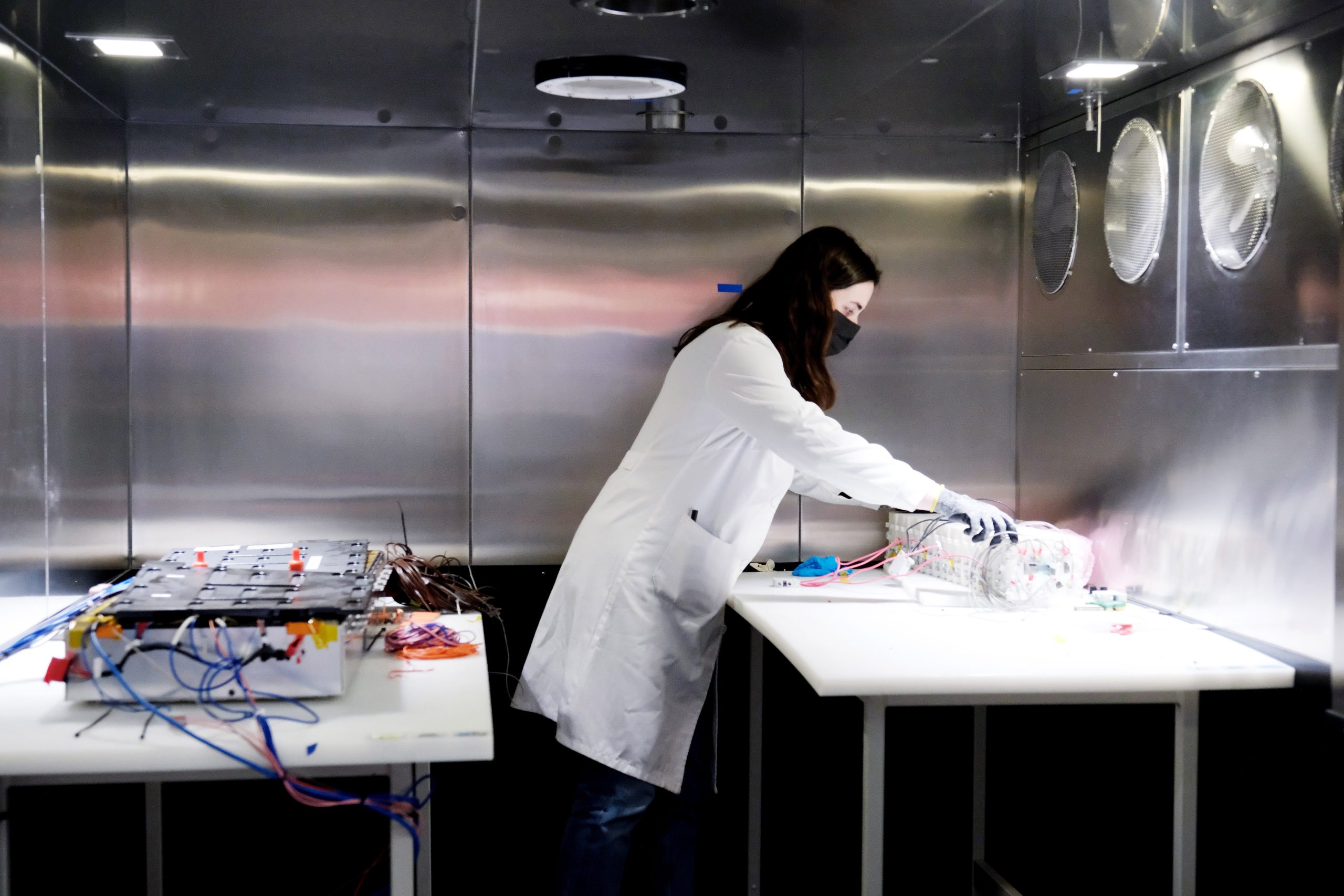 Scientist operating laboratory equipment with multiple cables, representing life cycle assessment research and digital tools for evaluating the environmental and social impact of energy technologies.
