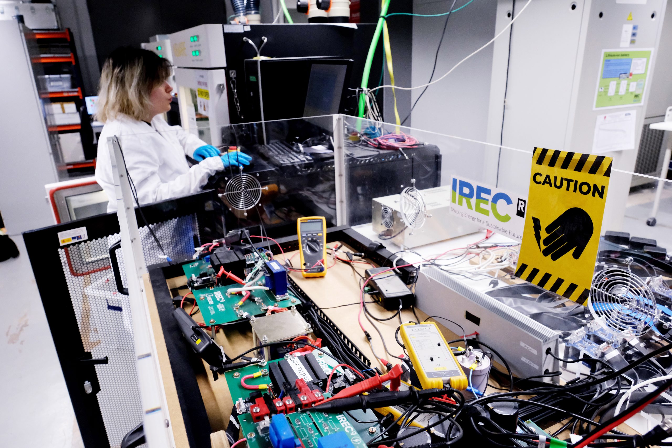 Scientist working with complex laboratory machinery with cables and electronic boards, representing advanced energy systems research, experimental validation and sustainable energy technology development.