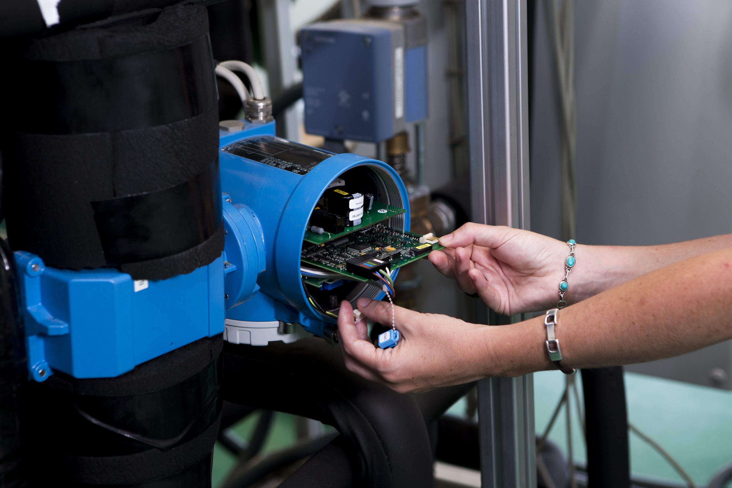 Researcher inserting a circuit board into laboratory equipment for urban energy simulation, supporting digital twin modelling of positive energy districts and climate-neutral neighbourhood planning.