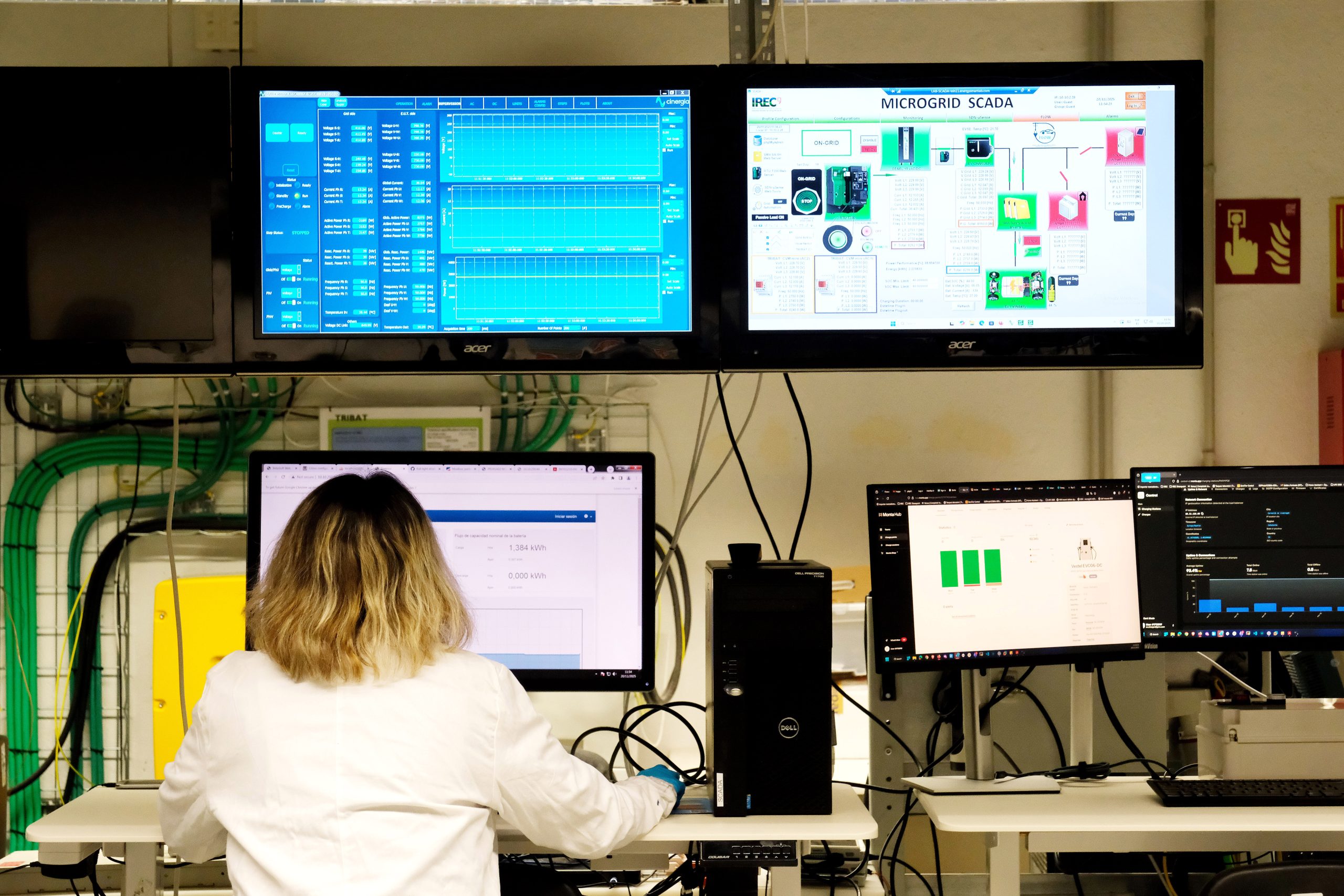Scientist working in an advanced energy research laboratory with multiple screens displaying data analysis, smart grid monitoring and renewable energy system performance.