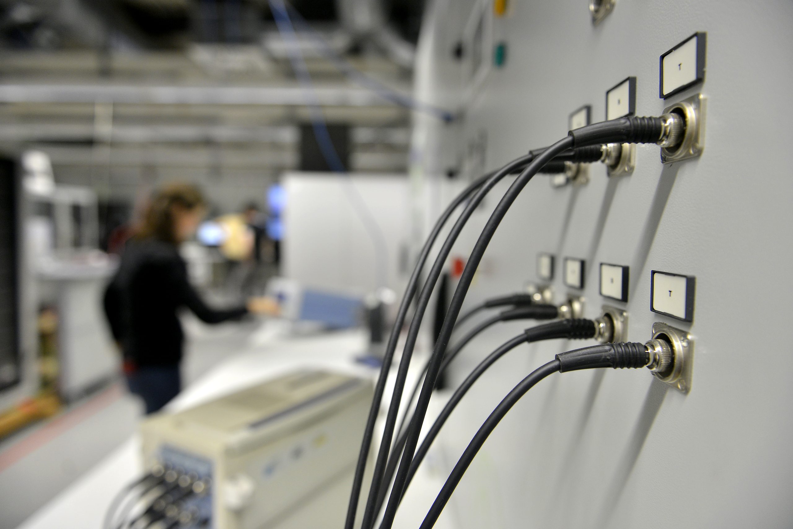 Scientist working with connected electrical cables and laboratory equipment for renewable energy integration, power grid stability testing and smart energy systems research.