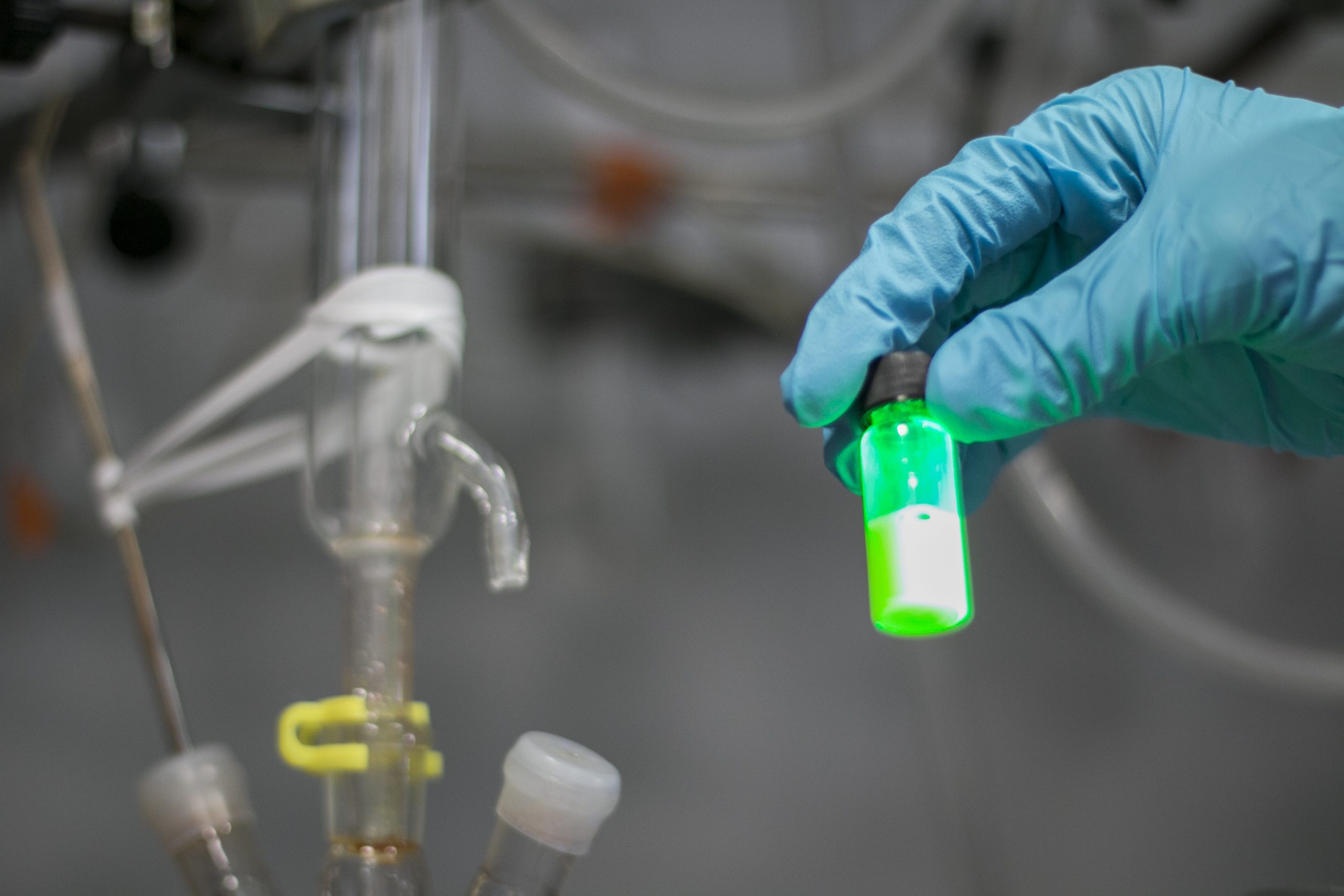 Laboratory container with green liquid, representing electrolyte solutions used in battery research and development of advanced energy storage systems.