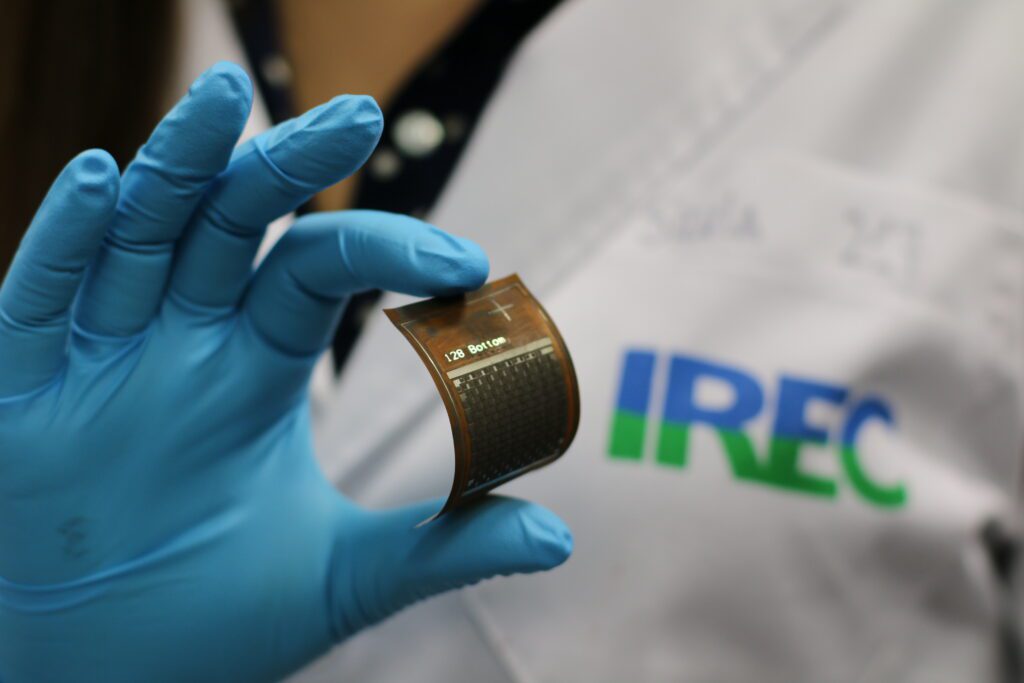 Investigador de IREC sosteniendo un dispositivo energético flexible en un laboratorio, representando la investigación avanzada en tecnologías de energías renovables, la innovación y soluciones sostenibles para abordar los retos energéticos globales y mejorar la competitividad industrial.